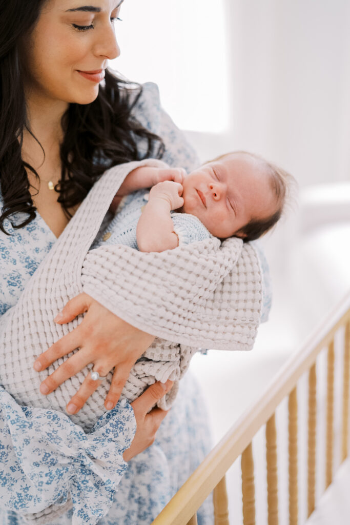 mom holding newborn baby in the nursery during her philadephia newborn photography session