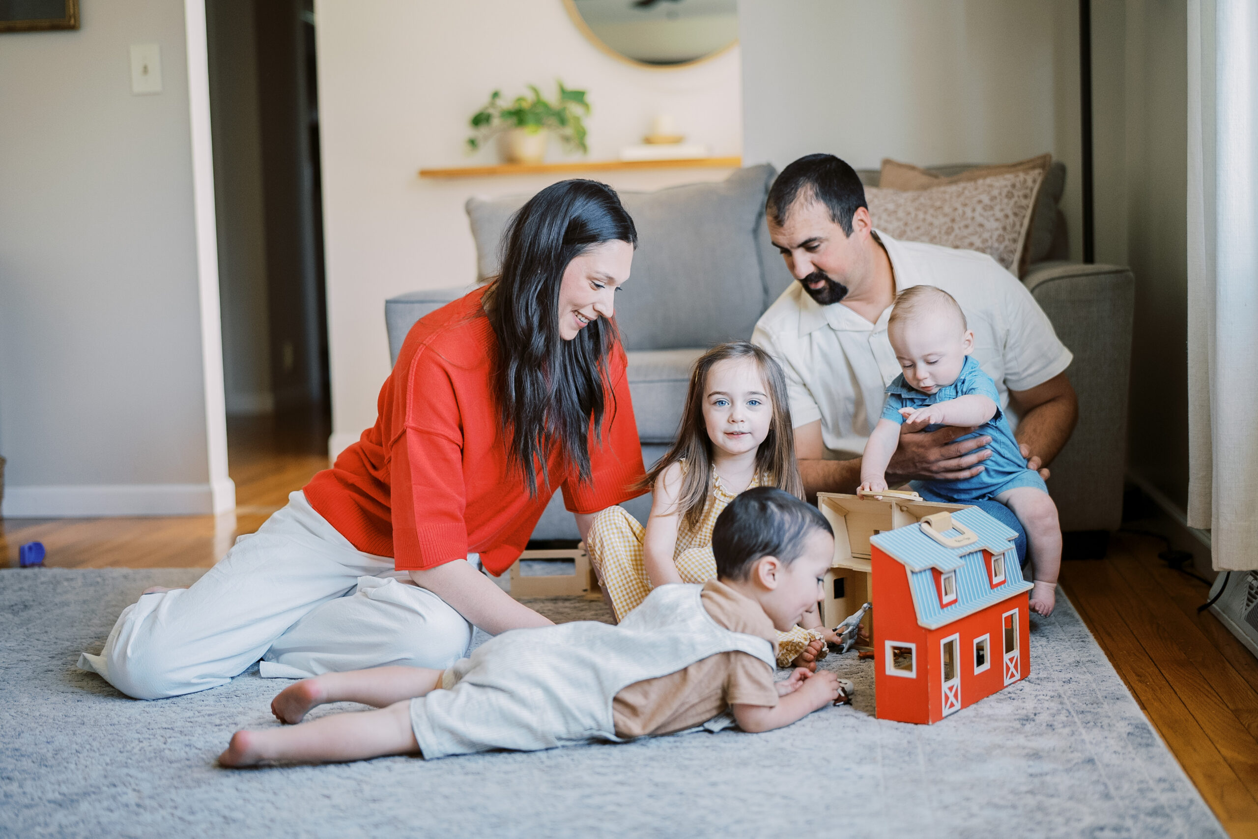 Family sits in their living room playing with a toy barn while they have fun during their Lancaster Family Photography Session