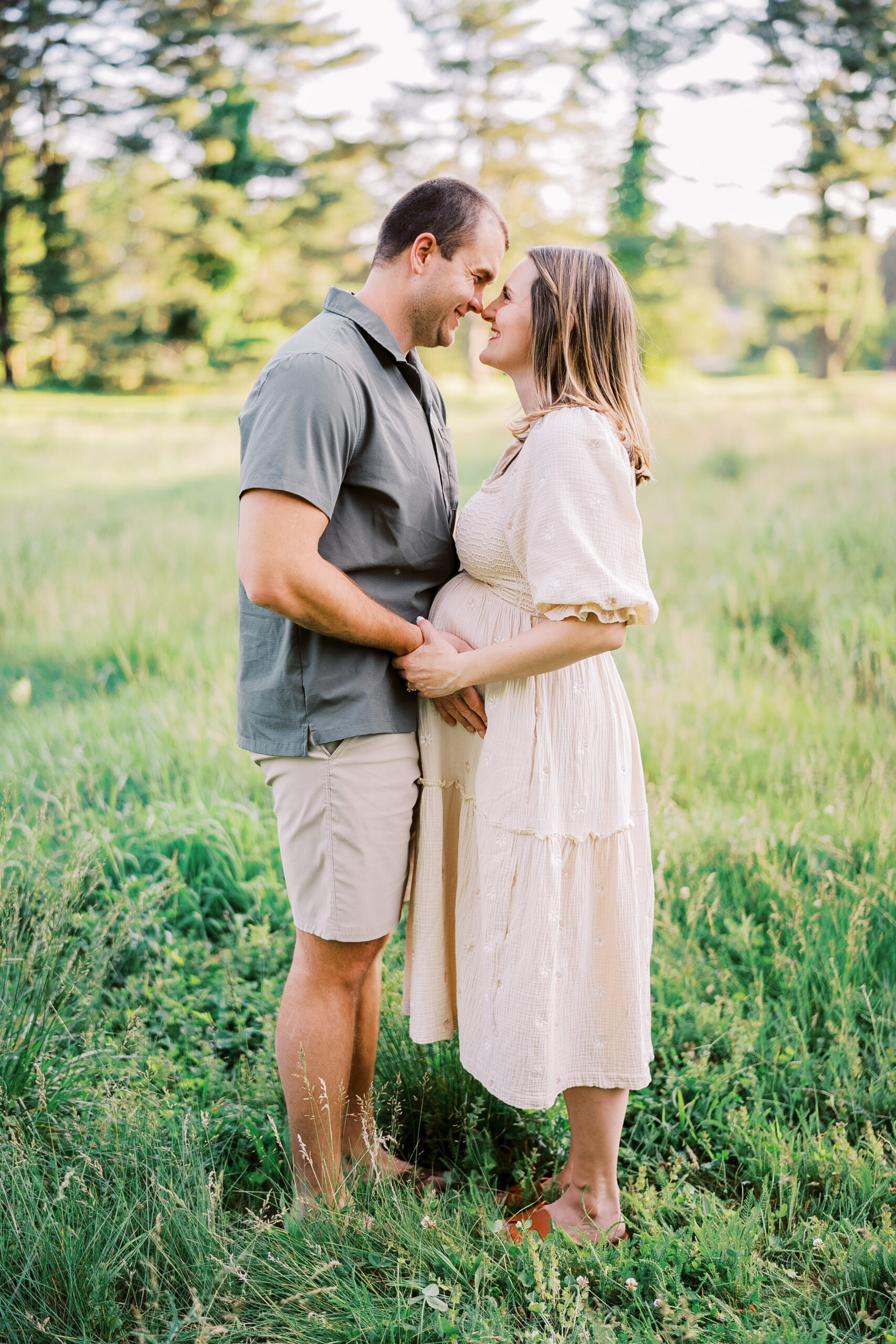 Pregnant mom stands with her husband in a field while they enjoy their lancaster maternity session