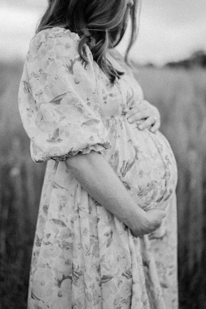 A pregnant woman stands in a field during her Philadelphia Maternity Session. This is a great example of what to wear for summer maternity photos.